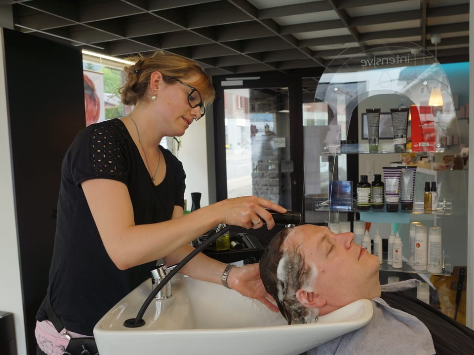 Eine Coiffeuse wäscht ihrem Kunden die Haare.