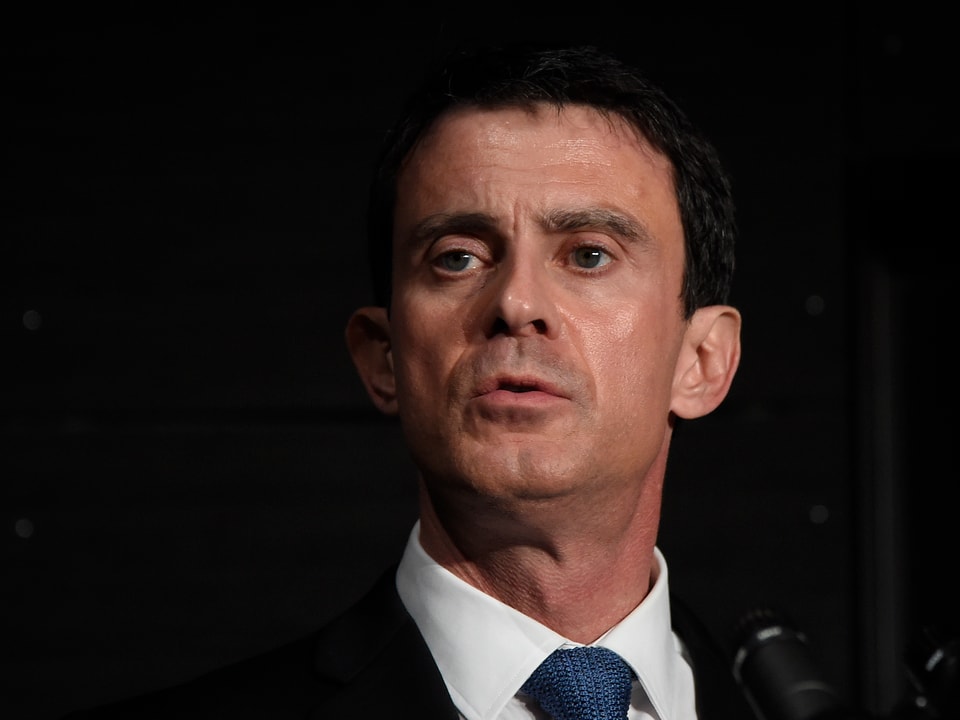 Manuel Valls vor dunklem Hintergrund