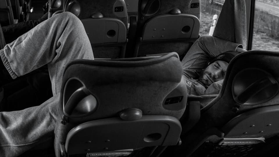 Ein Mann liegt in einem Mannschafts-Bus und schläft.