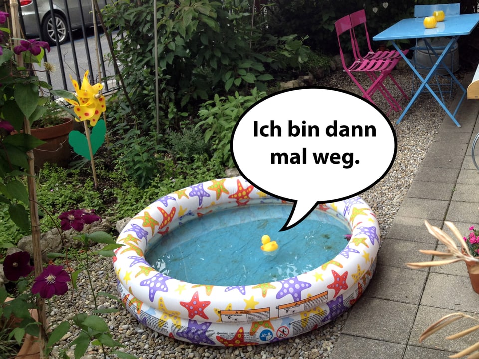 Eine Badeente schwimmt in einem Planschbecken in einem Vorgarten.