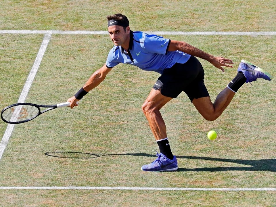 Roger Federer macht sich am Netz lang.