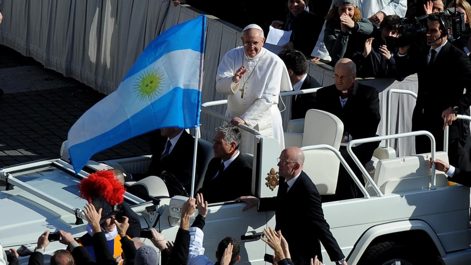 Papst Franziskus grüsst die Menge, eine argentinische Flagg im Vordergrund