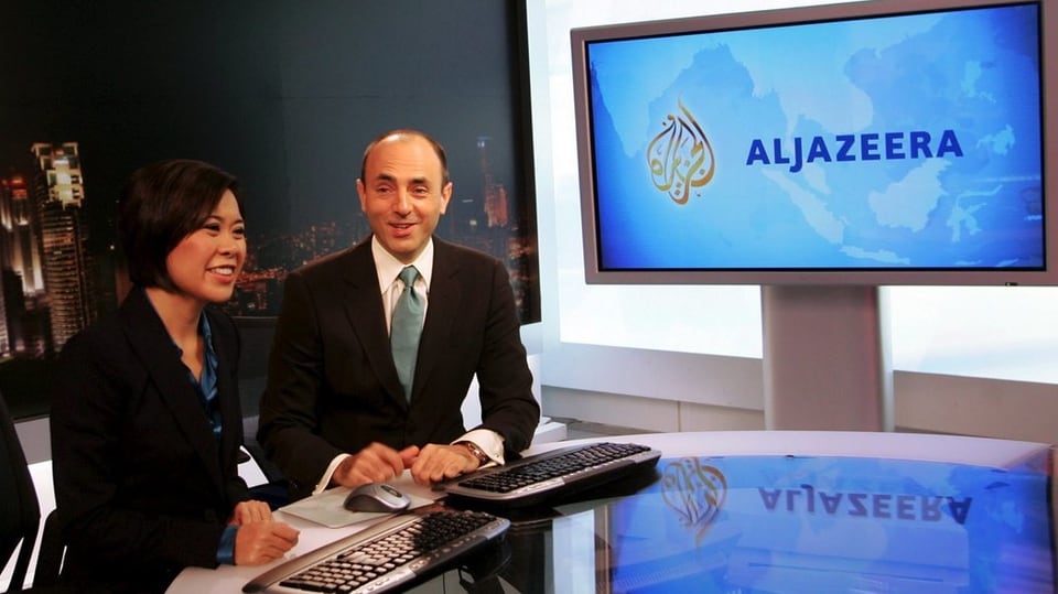Eine Moderatorin und ein Moderator vor einem Bildschirm mit «Al Jazeera»-Logo.