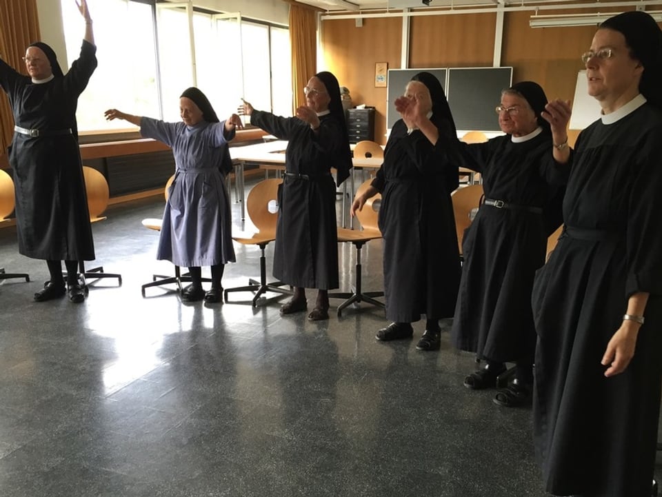 Nonnen stehen in einem Halbkreis und singen.