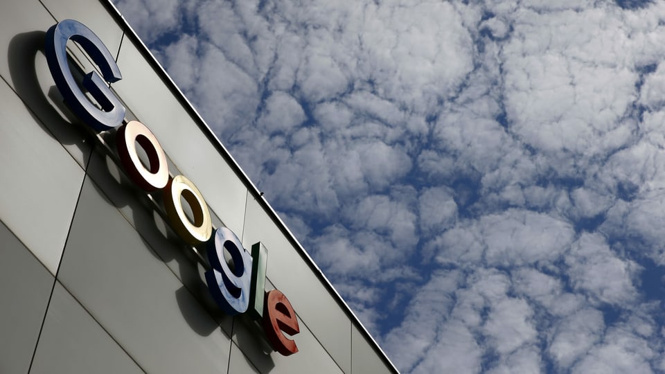 An einer grauen Gebäudewand hängt das Logo von Google.