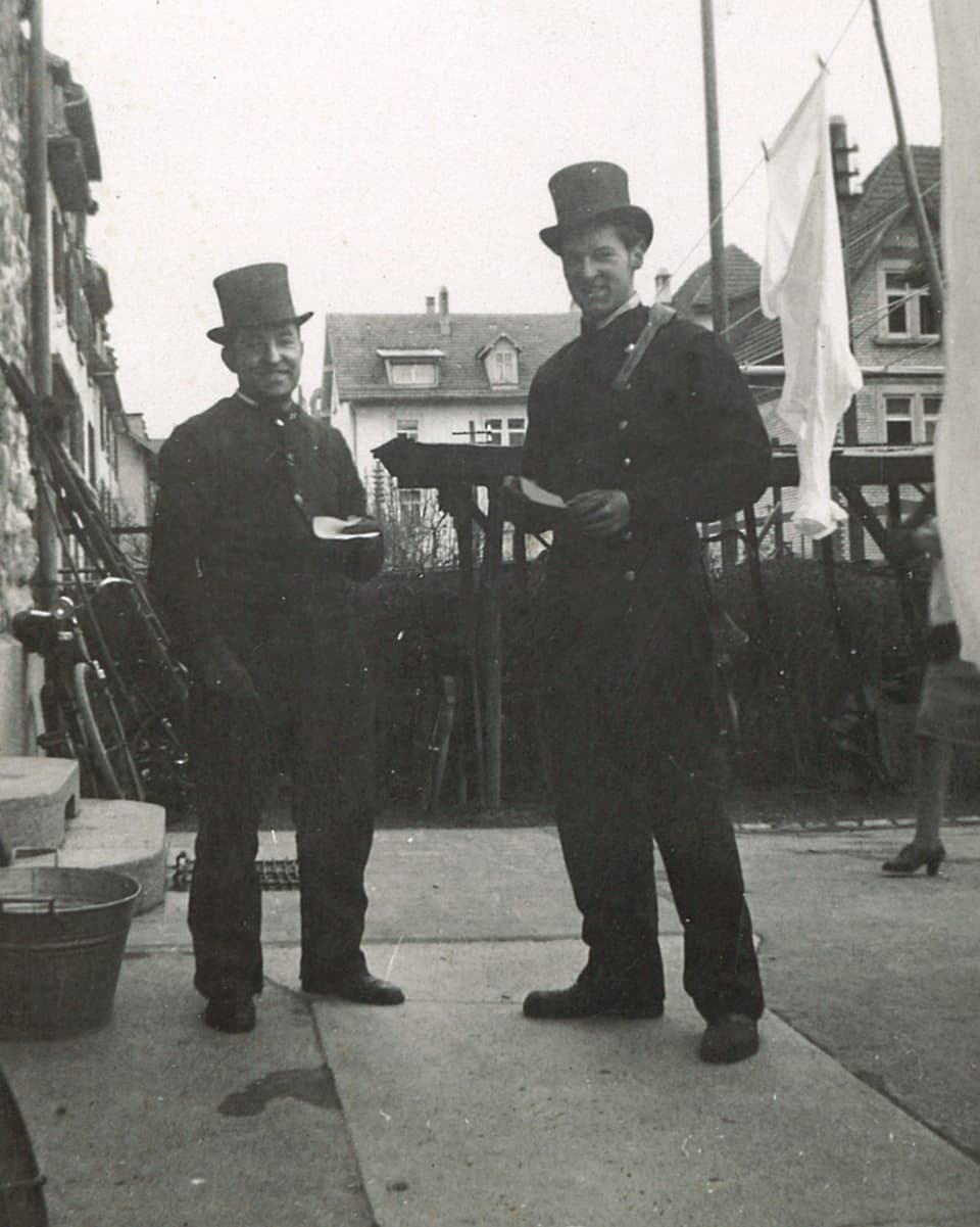 Schwarz-Weiss-Fotografie mit zwei Kaminfegern, die auf einer Terrasse stehen.