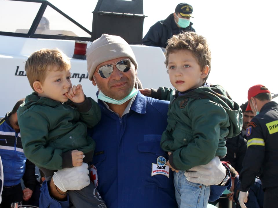 Mitarbeiter der griechischen Rettungskräfte mit zwei Kindern. 