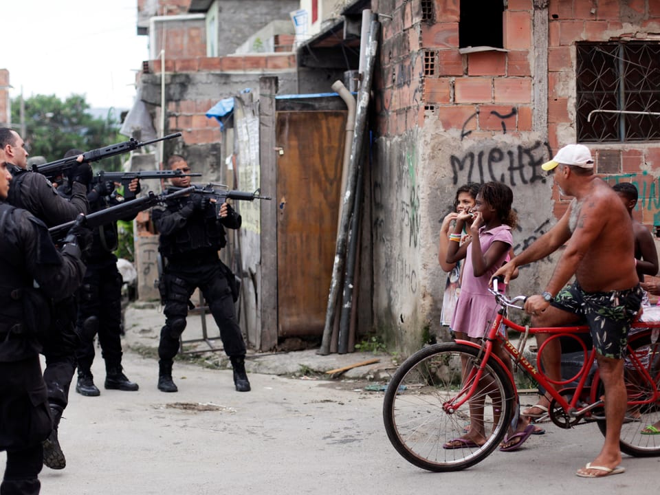 Sicherheitskräfte zielen mit ihren Waffen auf Favela-Bewohner.