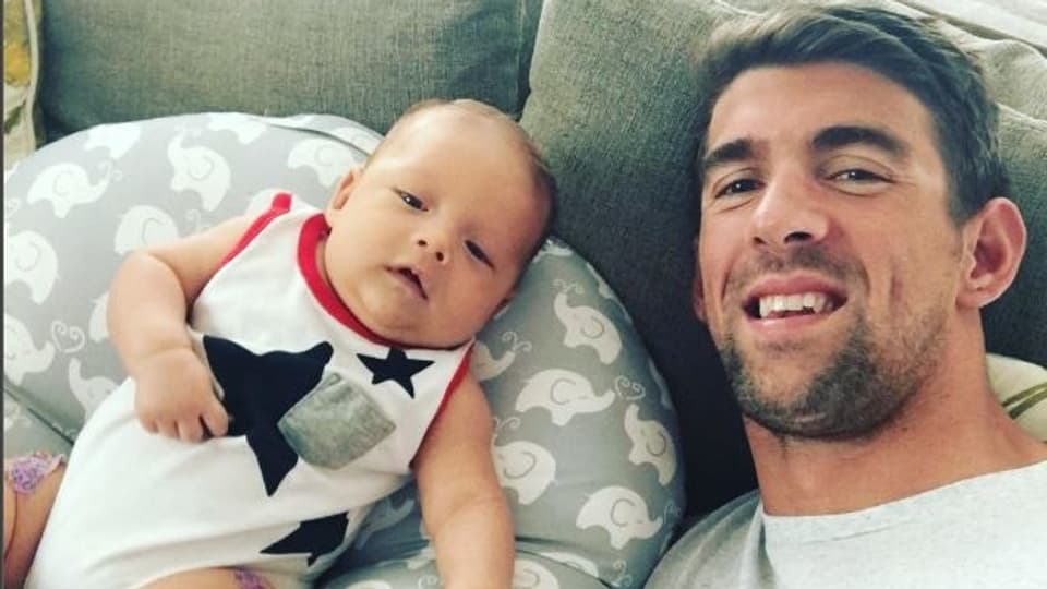 Baby und der Vater Michael Phelps liegen auf dem Sofa