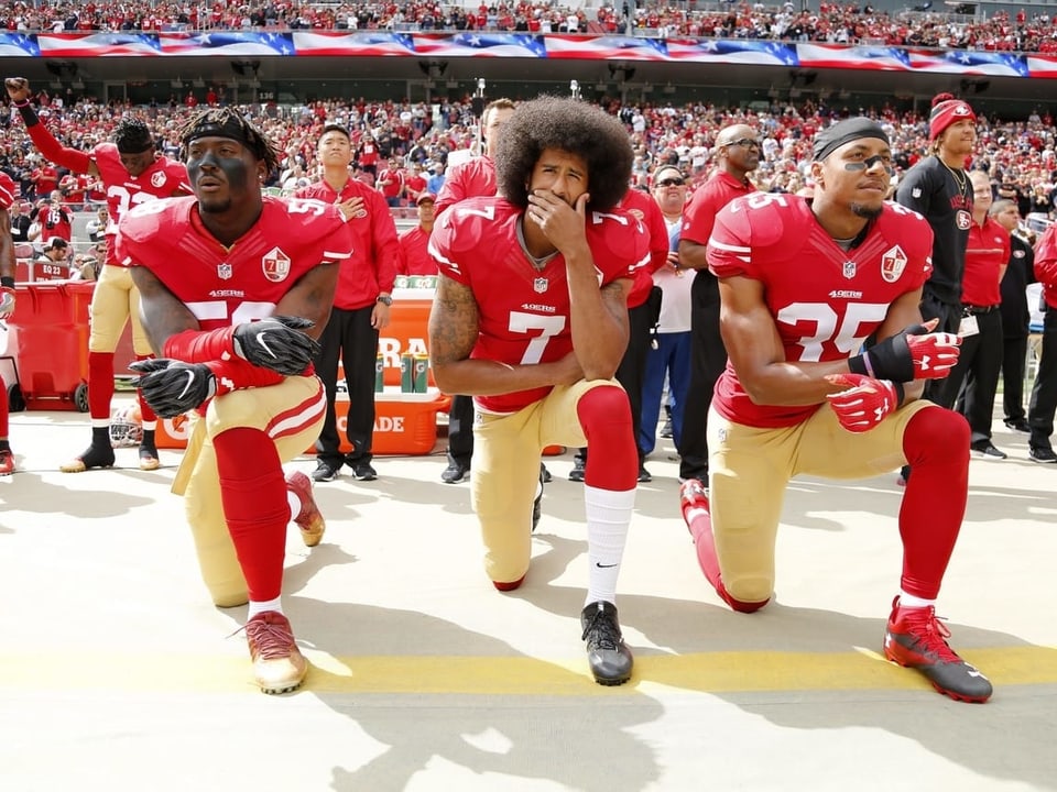 Aus Protest Colin Kaepernick (Mitte) und zwei seiner Teamkollegen gehen während der US-Hymne in die Knie.