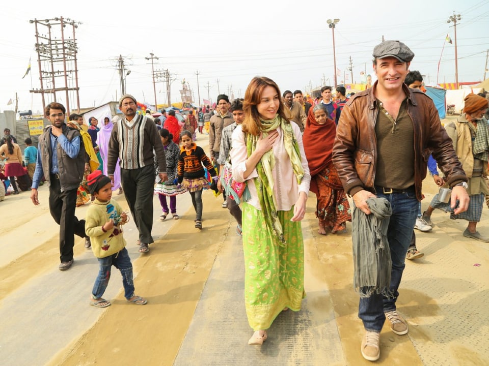 Ein europäisches Paar in indischer Kleidung, vor einer Menschenmenge.