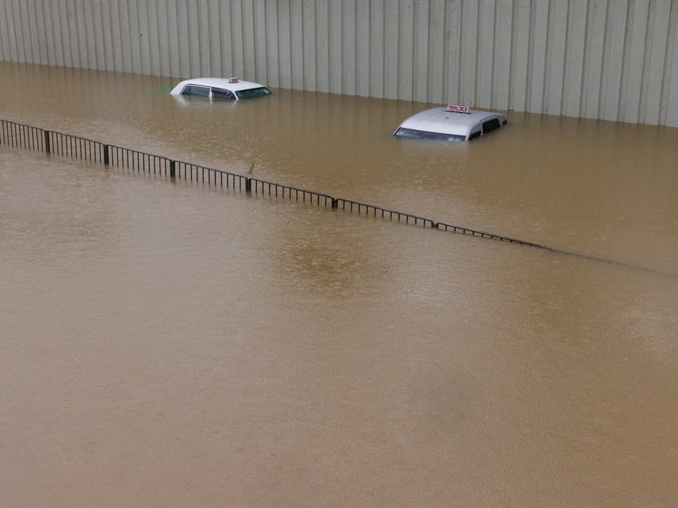 Zwei überschwemmte Taxis, nur das Dach schaut noch aus dem braunen Wasser