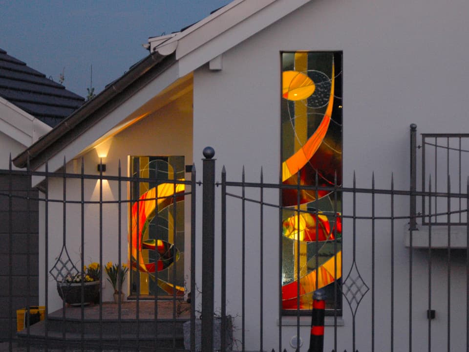 Ein Haus mit zwei kunstvoll gestalteten bunten Glasfenstern.