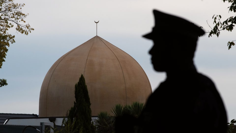 EIn Polizist vor der Kuppel einer Moschee