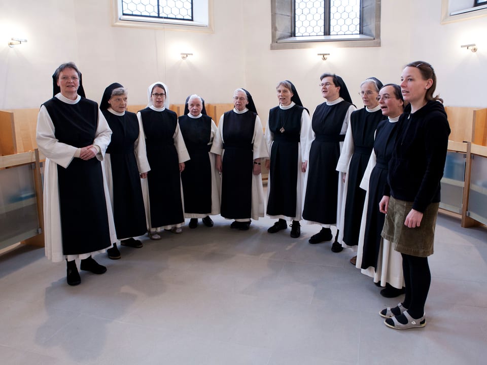 Eine Gruppe Nonnen steht in einem Halbkreis in einer Kirche
