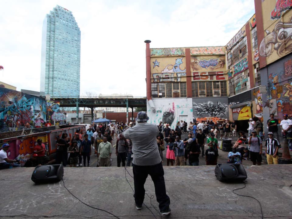 Ein Mann mit Mikrofon auf einer Bühne im Freien.