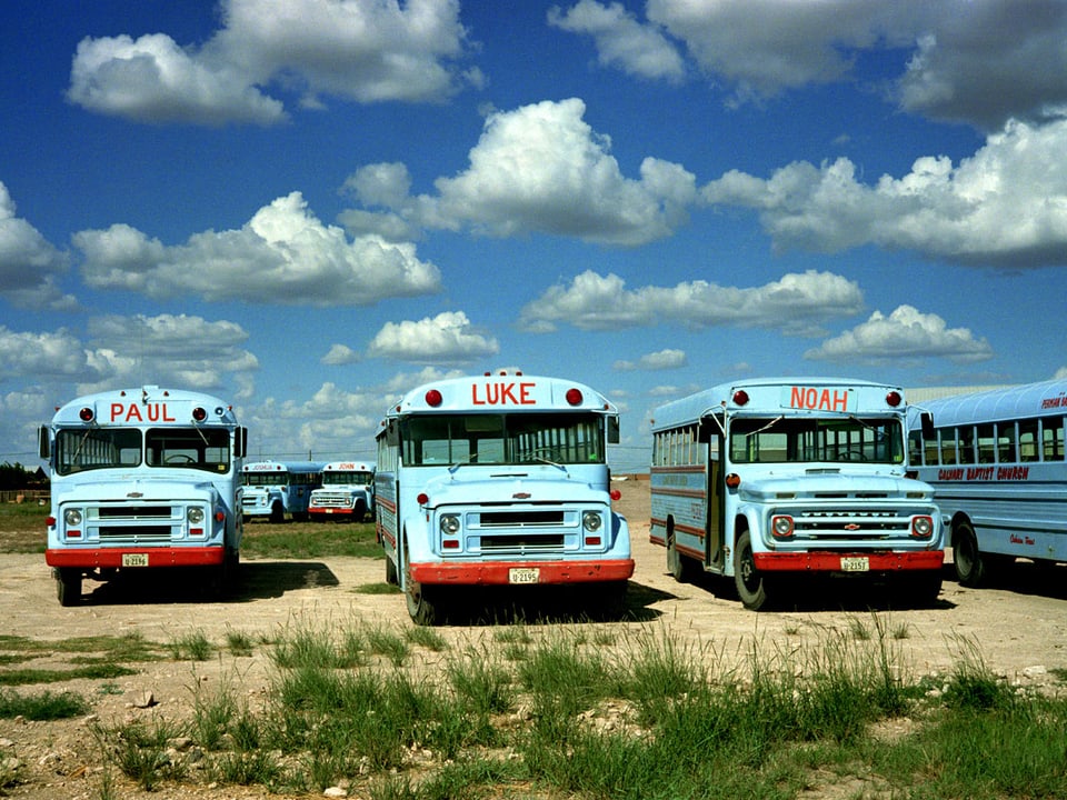 Drei hellblaue Trucks stehen auf einem verlassenen Platz, darüber ein Himmel mit Wolken. 