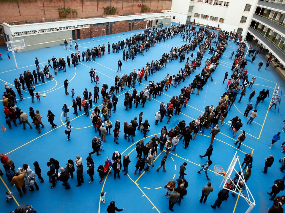 Katalanen stehen Schlage vor einem Wahllokal auf einem Sportplatz in Barcelona.