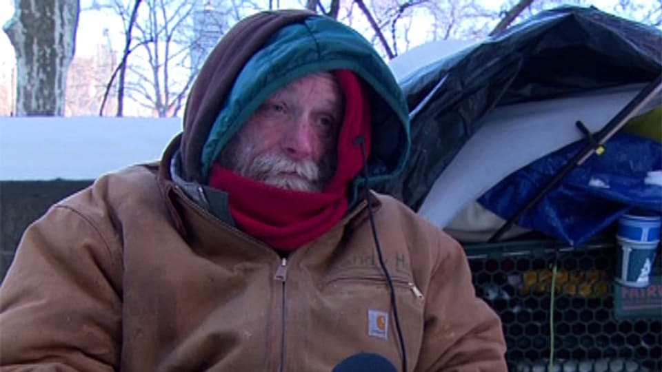 Ein Obdachloser in Mantel und Schal.