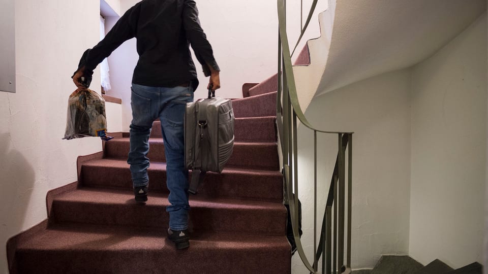 Ein Mann geht mit einem Koffer eine Treppe hoch.