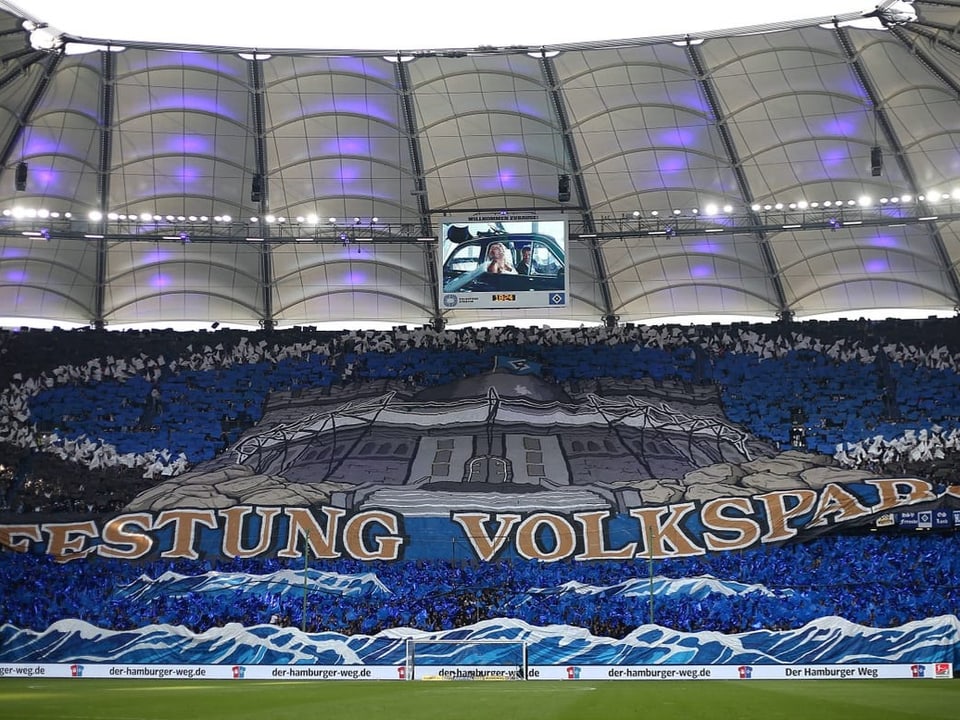 Fussballstadion mit Fans und einem grossen Transparent mit der Aufschrift 'FESTUNG VOLKSPARK'.