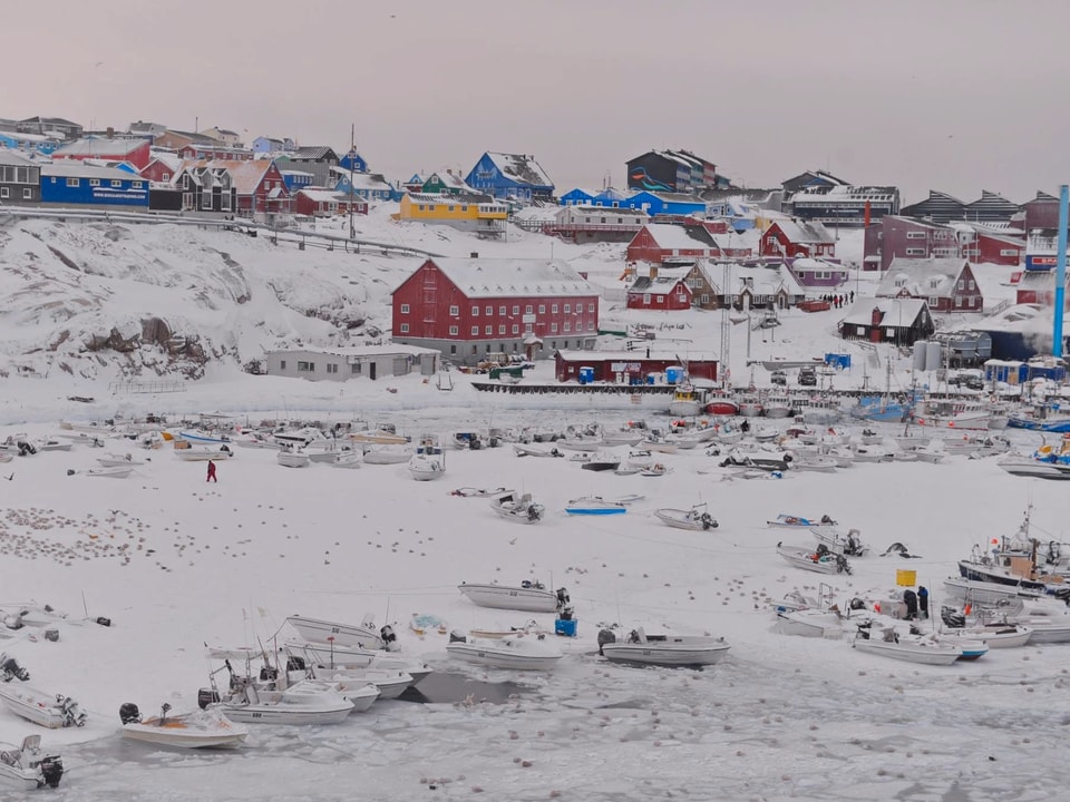 Schneelandschaft mit ein paar Häusern, Schiffen im Schnee statt im Wasser. 