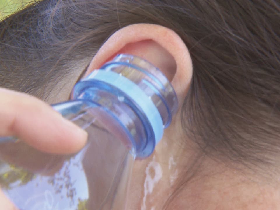 Mit einer Wasserflasche wird das Ohr ausgespült.