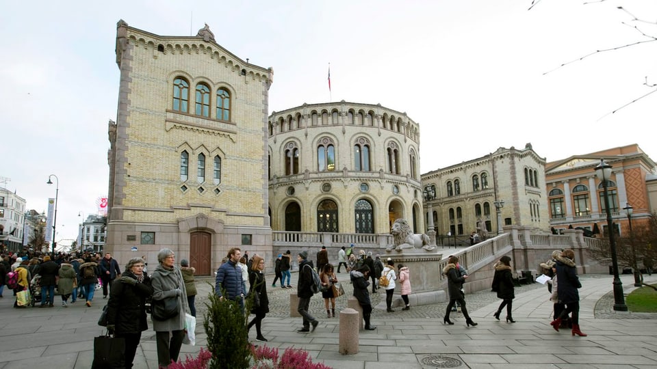 Am Parlamentsgebäude in Oslo gehen Menschen vorbei.