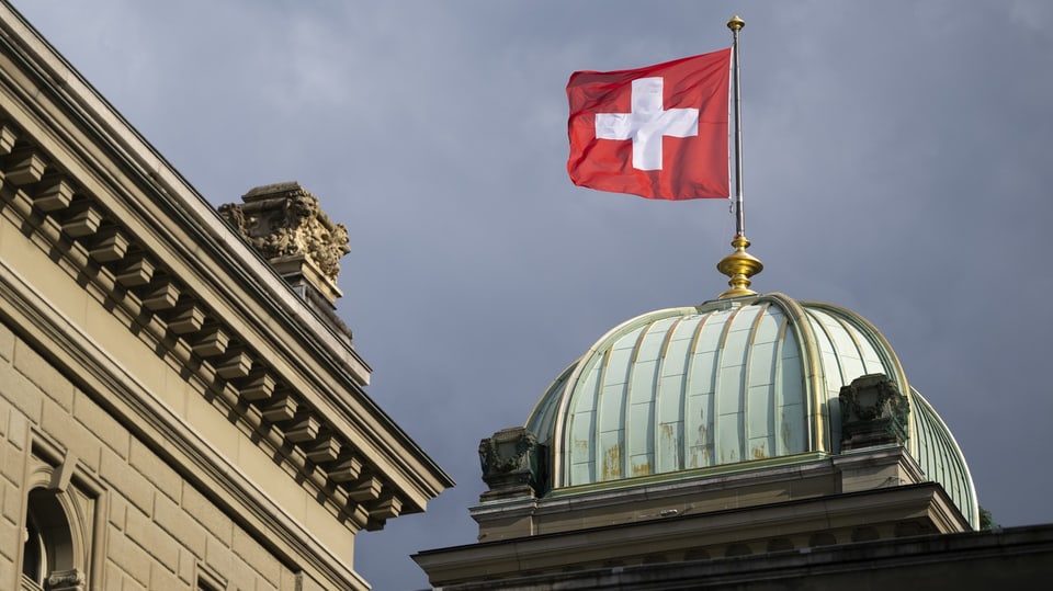 Blick auf Dach des Bundeshauses mit wehender Schweizer Flagge