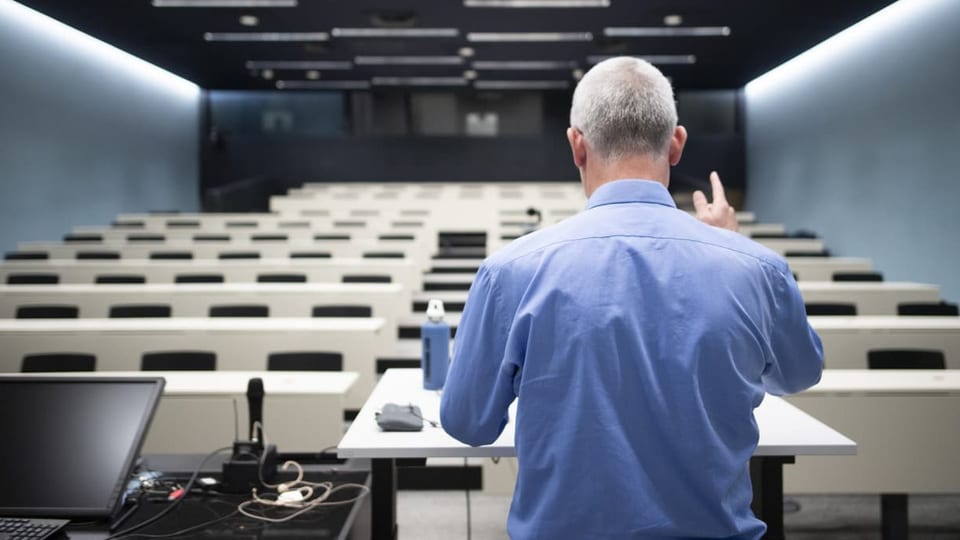 Ein Lehrer unterrichtet im leeren Saal vor der Webcam.