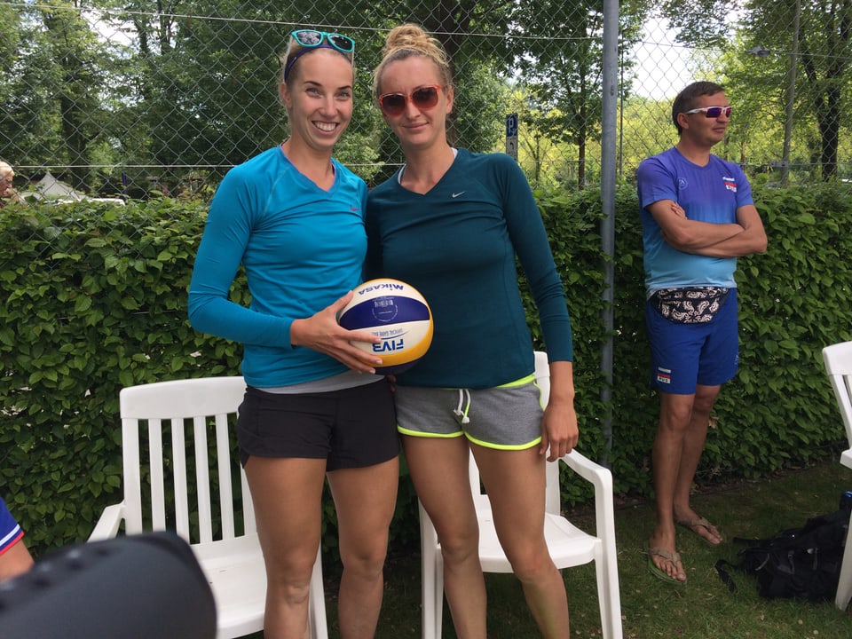 Zwei grosse, blonde Frauen posieren mit einem Volleyball in der Hand.