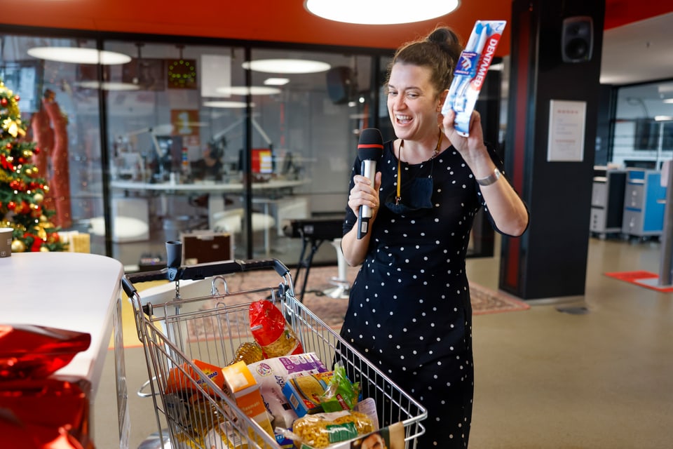 Frau mit Mikrofon vor Einkaufswagen