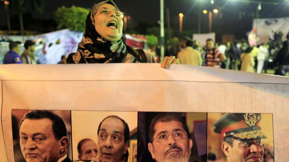 Demonstrantin hält ein Banner mit Bilder der Exponenten Ägyptens.