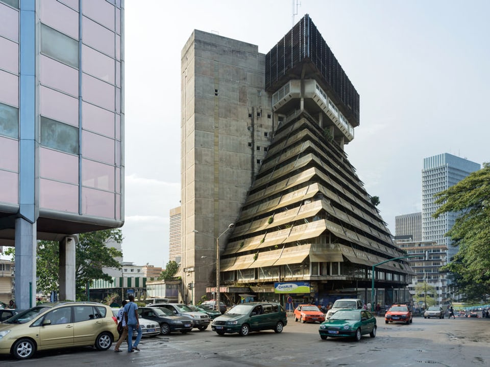 Blick auf ein Gebäude, das aus einer pyramidenförmigen und aus einer länglichen Struktur besteht. 