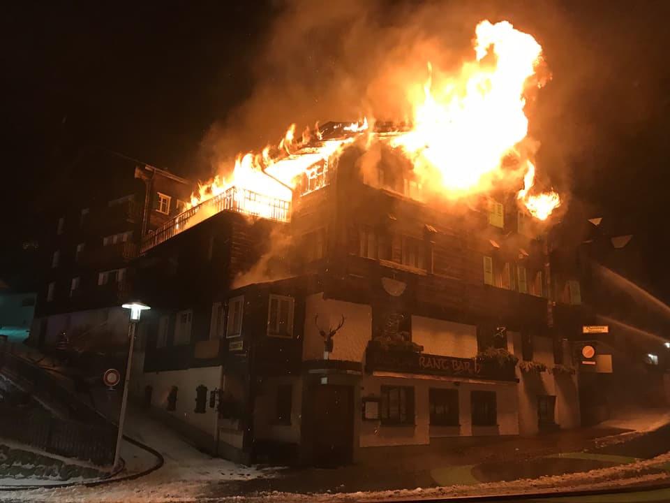 Gebäude in Brand, Flammen dringen aus den Fenstern heraus.
