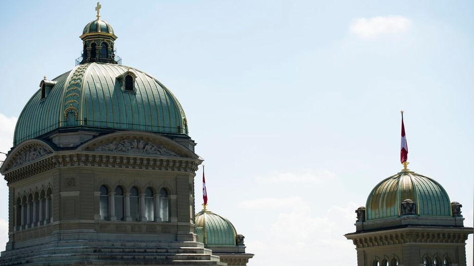 Blick auf die Bundeshauskuppeln mit Schweizer Fahne.