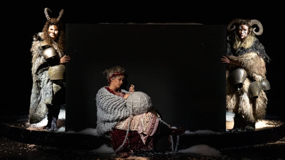 Junge Frau in Wollkleidung, umrahmt von zwei gehörnten Wesen in Winterfellen.