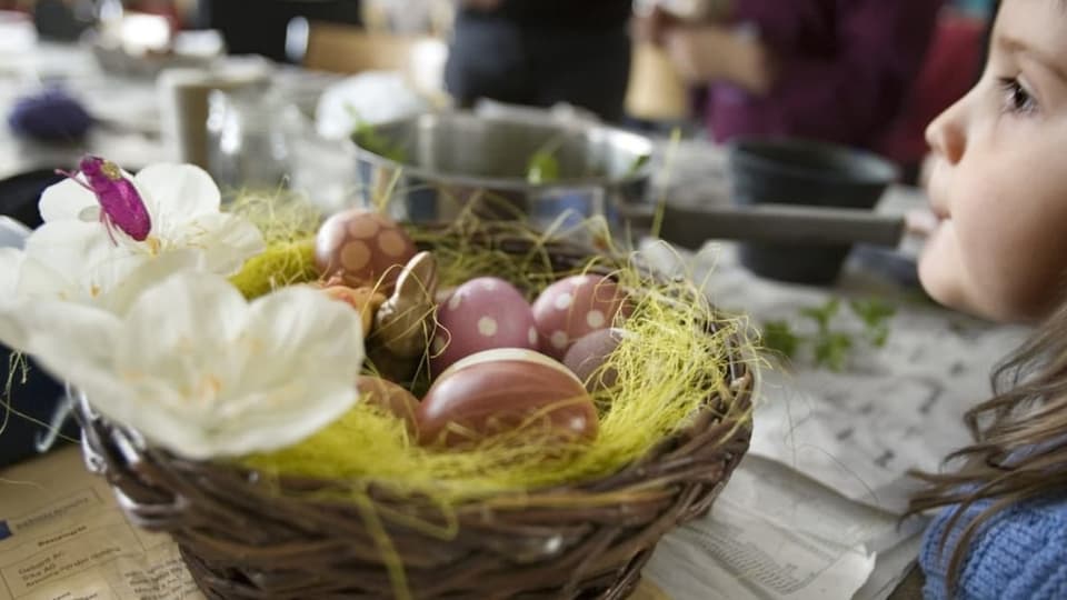 Kind neben einem Osternest.