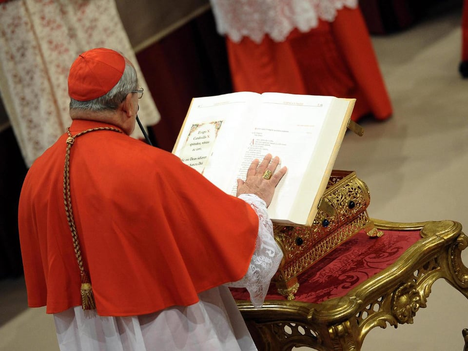 Kardinal legt Hand auf die Bibel.