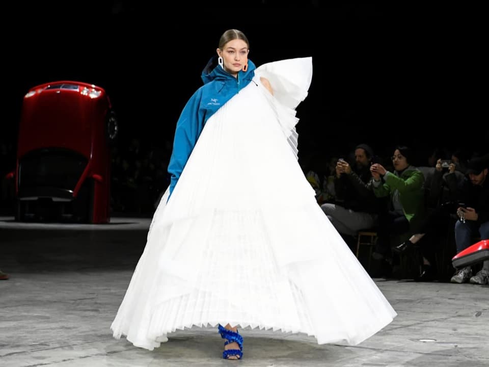Weisses Model in einem weissen Kleid, oben ein Teil blaue Jacke.