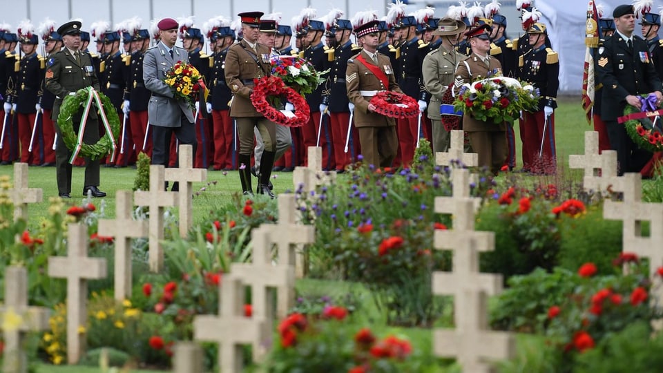 Soldaten mit Kränzen auf einem Soldatenfriedhof.