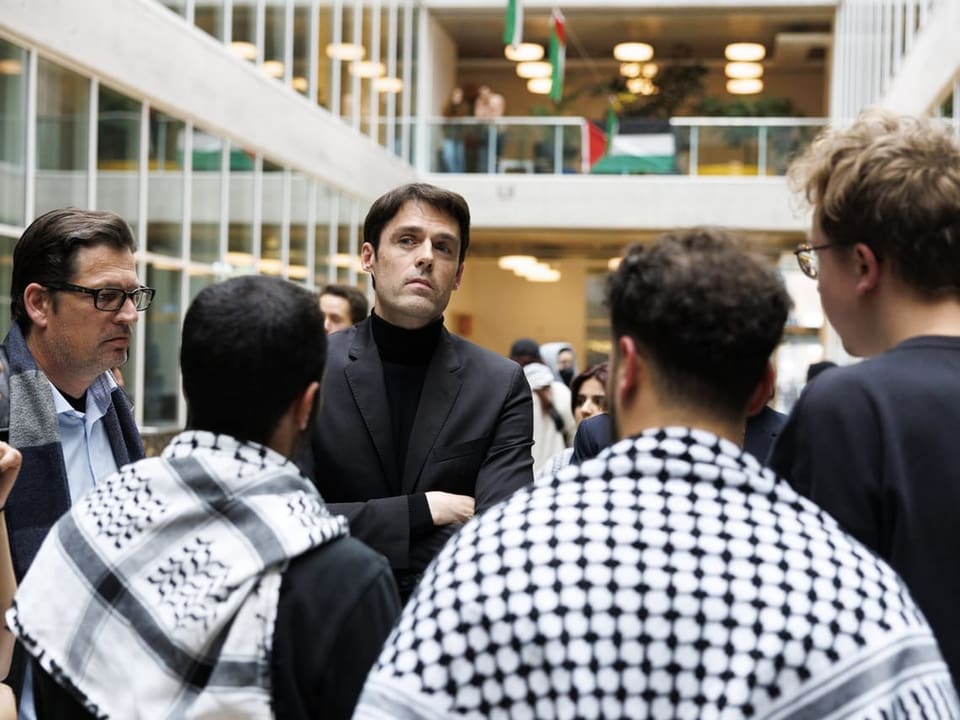 Priester spricht mit einer Gruppe junger Männer in einem öffentlichen Gebäude