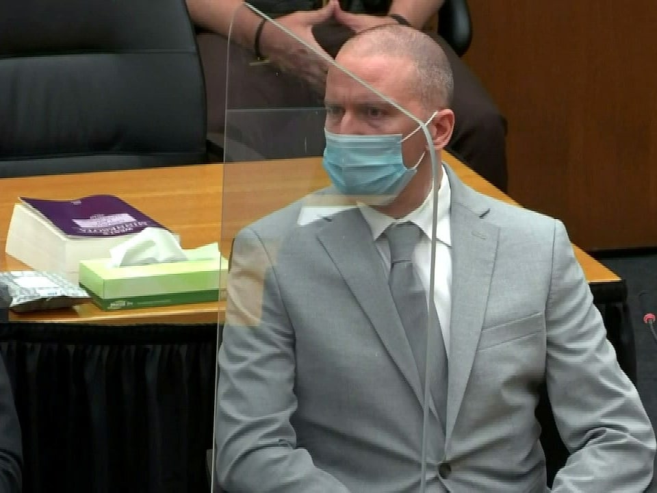 Mann in grauem Anzug und mit Gesichtsmaske (Derek Chauvin) sitzt in einem Gerichtssaal.