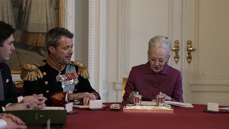 Frau sitzt an einem Tisch, daneben ein Mann mit Ehrenabzeichen