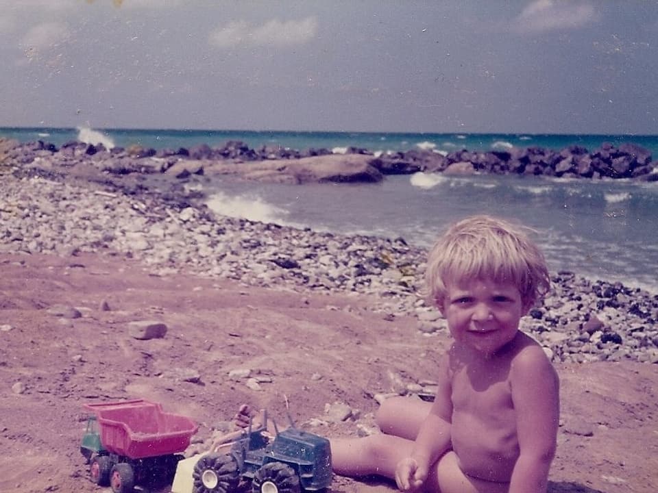 Ein kleiner Junge sitzt am Strand.