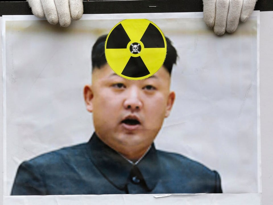 Kim Jong Un auf einem Plakat, ein Atom-Logo klebt darüber.