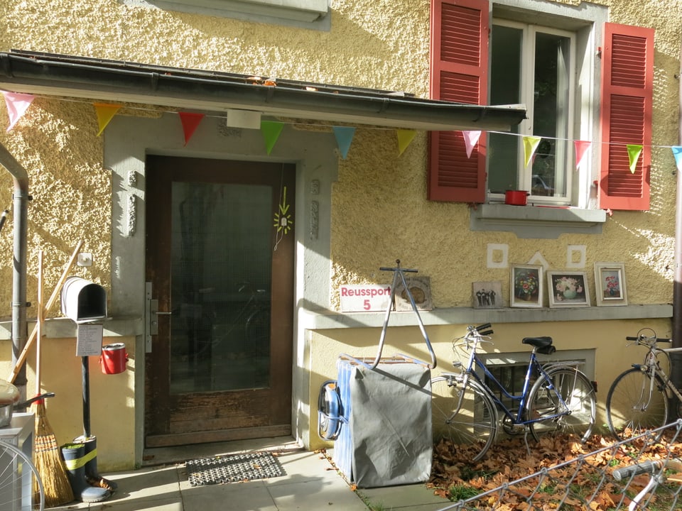 Eingangsbereich des gelben Hauses mit Velo und Briefkasten