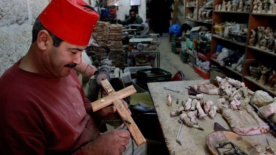 Ein Palästinenser schnitzt ein Kruzifix. Er verkauft seine Werke als Souvenirs an Touristen.