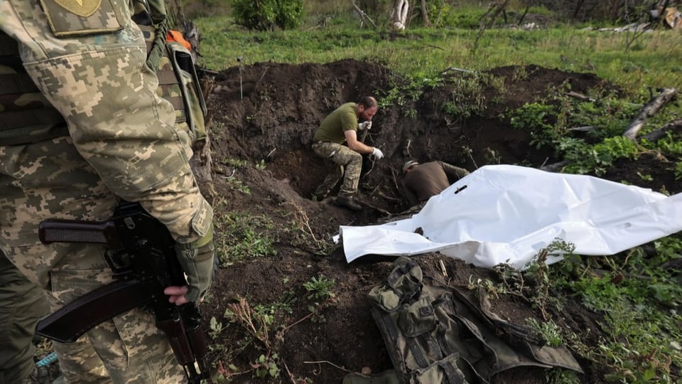 Ukrainische Soldaten exhumieren eine Leiche (26.09.22)