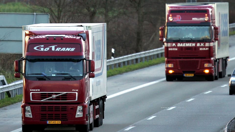 Zwei weinrote Lastwagen rollen auf der Autobahn